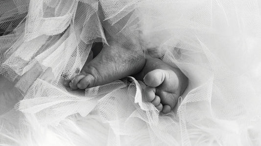 zwart wit afbeelding van babyvoetjes te midden van lichtgekleurd tule
