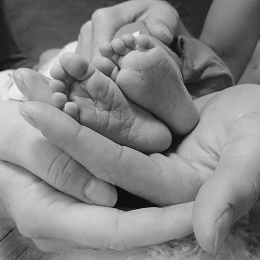 zwart wit afbeelding van handen vader en moeder met babyvoetjes