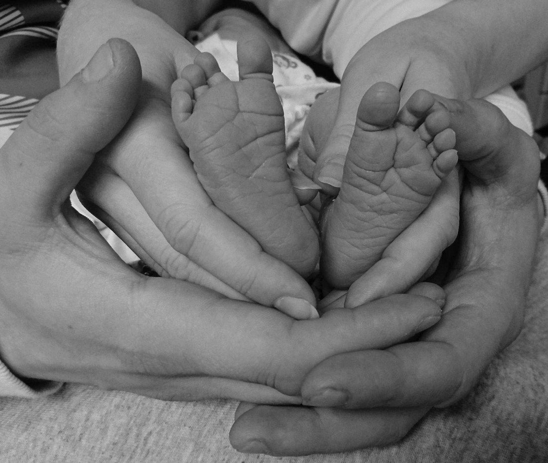 handen van vader en moeder met babyvoetjes, vluchtkoffer inpakken voor de bevalling
