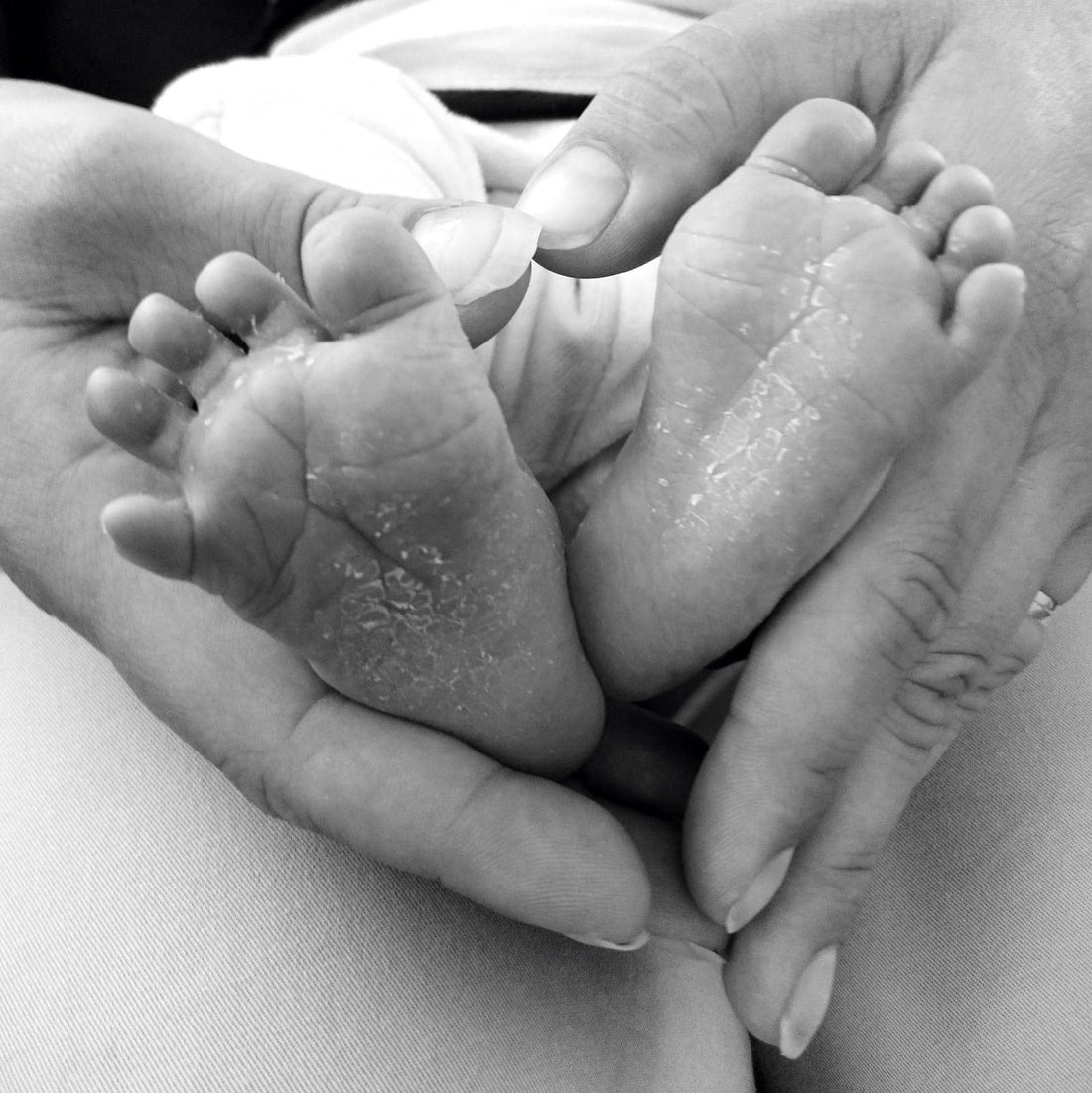 zwart wit afbeelding van moeder handen met babyvoetjes in hartvorm