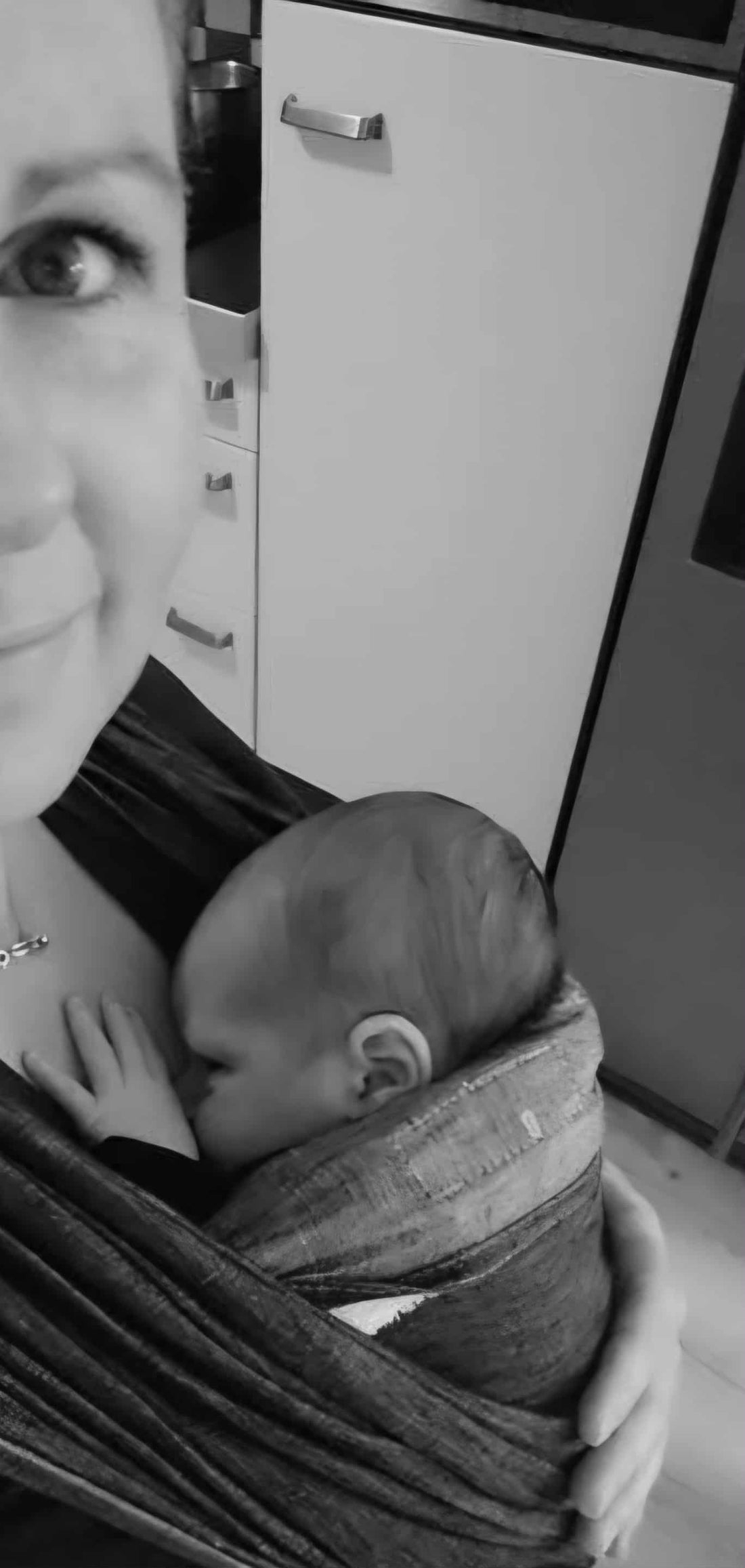 moeder draagt baby in draagdoek in drukke omgeving, rust en veiligheid door nabijheid