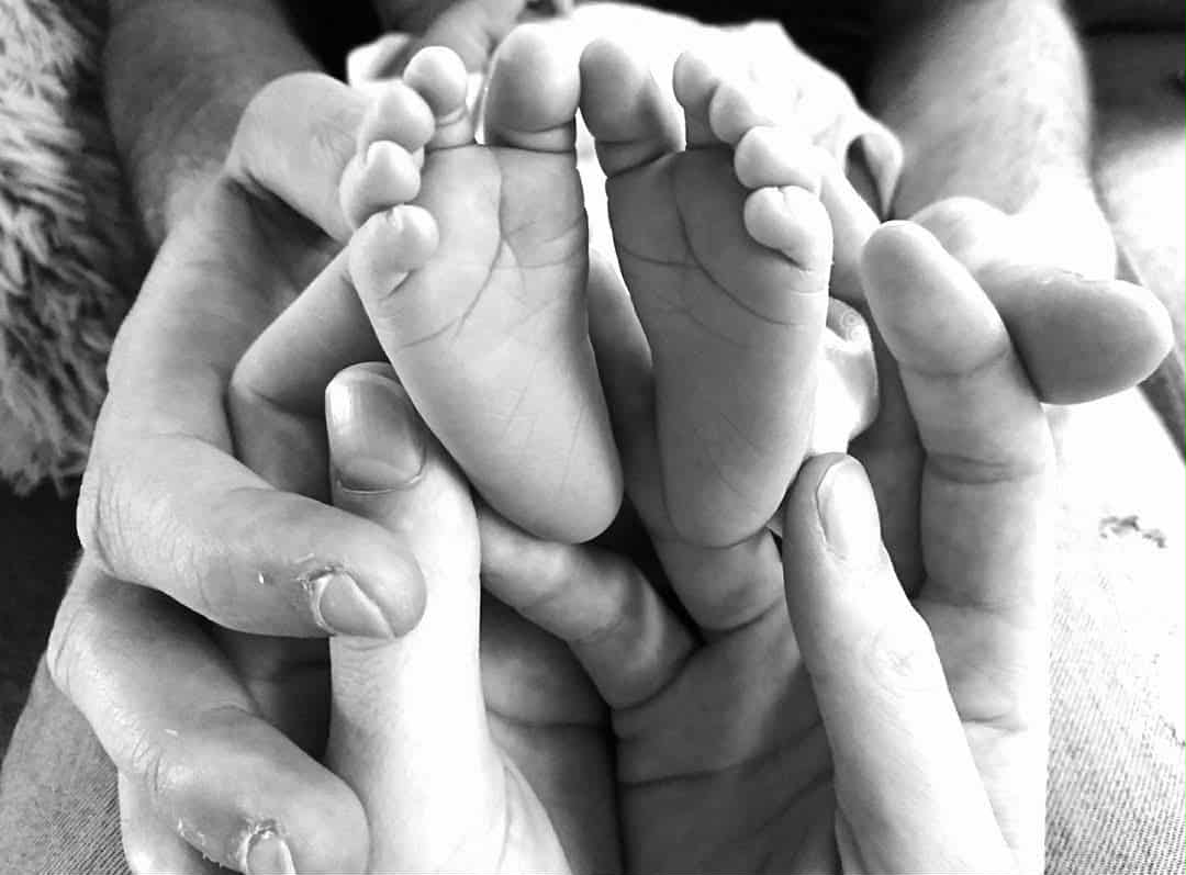 zwart wit afbeelding van handen ouders met babyvoetjes