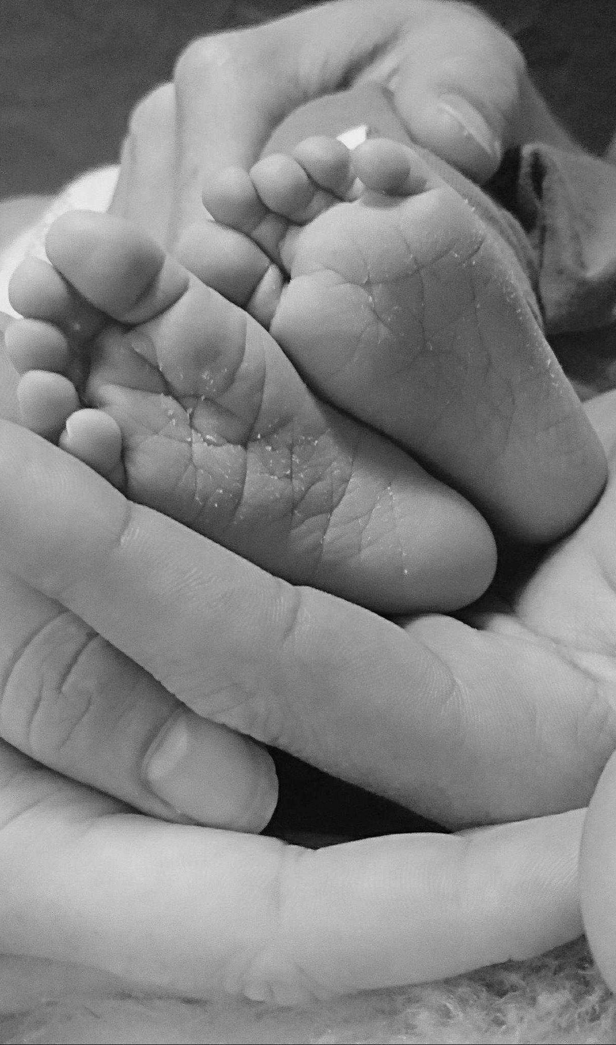 Kleine babyvoetjes in de handen van vader en moeder